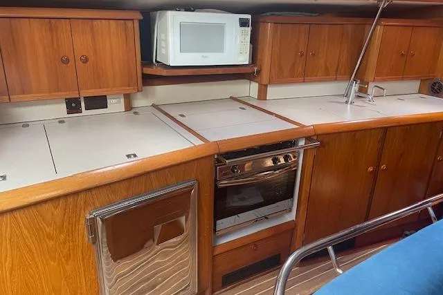 Ligera Yacht Photos Pics Interior of 2002 Jeanneau Sun Odyssey 45.2 yacht kitchen with wooden cabinets and appliances.