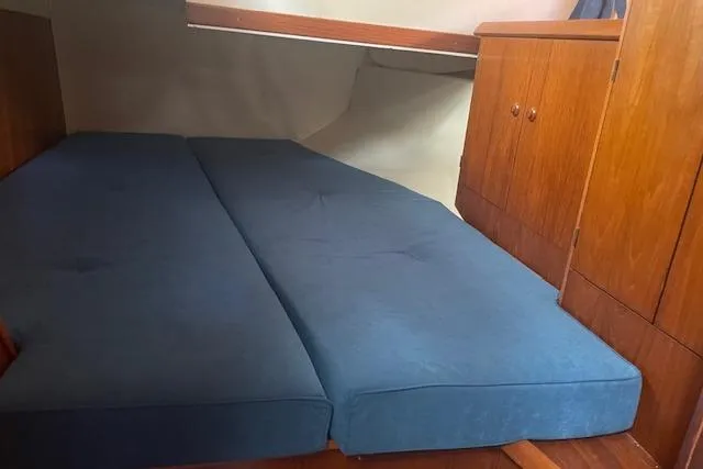 Ligera Yacht Photos Pics Cabin interior of 2002 Jeanneau Sun Odyssey 45.2 with blue cushions and wooden cabinetry.