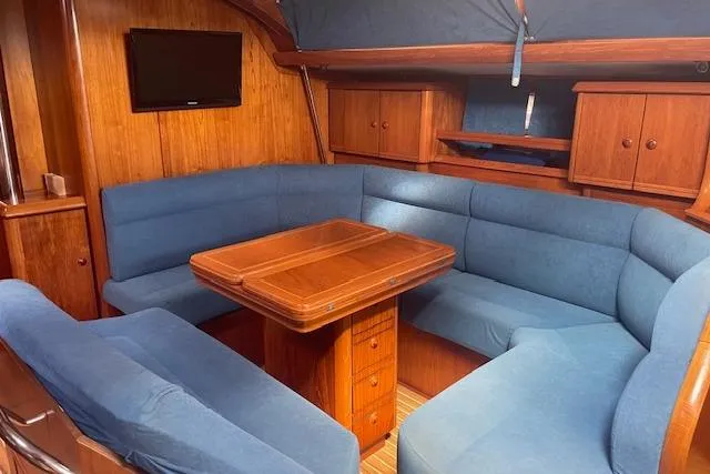 Ligera Yacht Photos Pics Interior of 2002 Jeanneau Sun Odyssey 45.2 yacht with blue seating and wooden table.