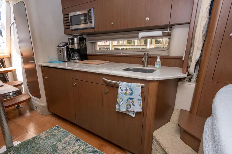 Latitude Adjustment Yacht Photos Pics Interior of 2013 Sea Ray 370 Sundancer yacht with kitchenette, featuring sink, microwave, and coffee maker.