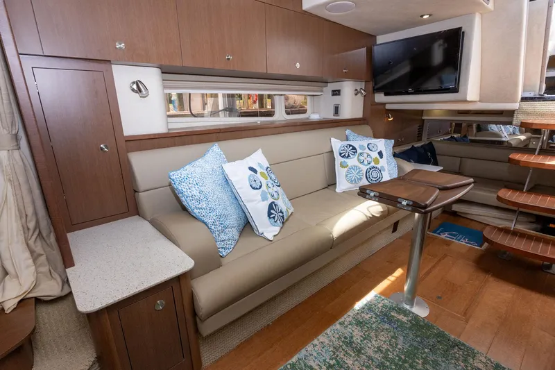 Latitude Adjustment Yacht Photos Pics Interior of 2013 Sea Ray 370 Sundancer with beige seating, decorative pillows, and a mounted TV.