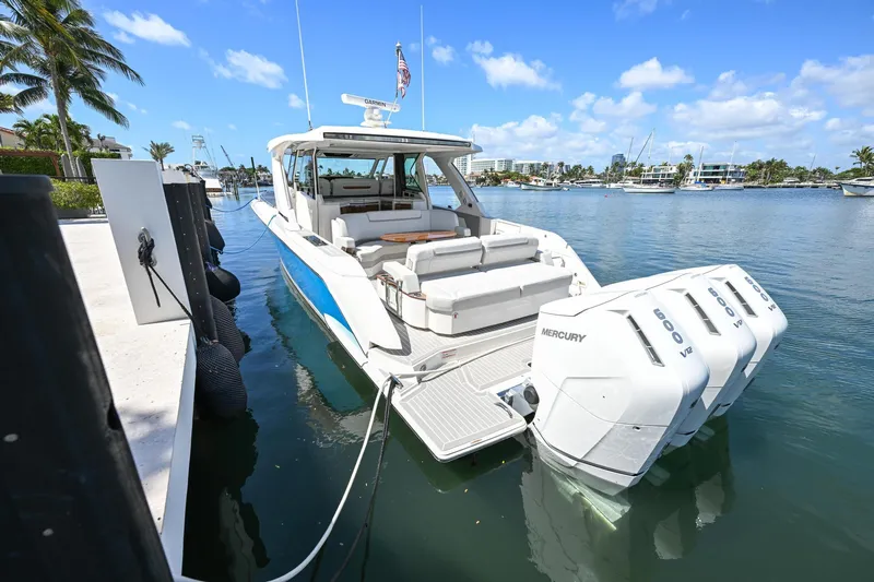  Yacht Photos Pics 2023 Tiara Yachts 48 LS docked, featuring triple Mercury engines, in a sunny marina setting.