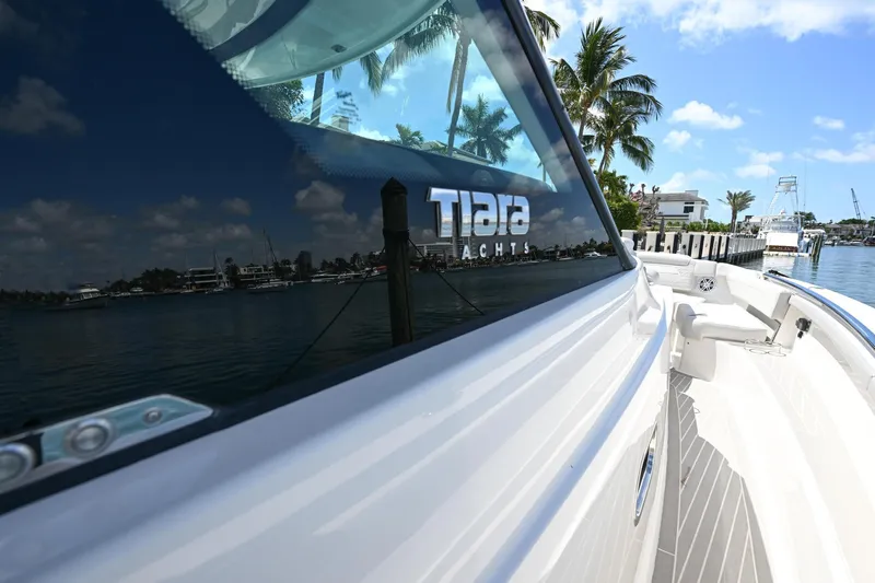  Yacht Photos Pics 2023 Tiara Yachts 48 LS reflecting water and palm trees, docked in a sunny marina.