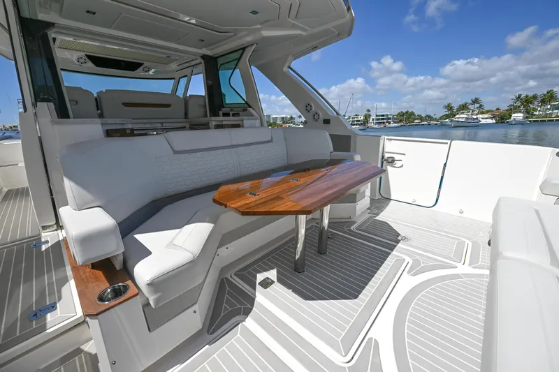  Yacht Photos Pics 2023 Tiara Yachts 48 LS interior with elegant seating and wooden table, docked by the water.