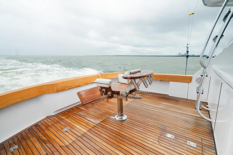 Water's Edge Yacht Photos Pics 2005 Hatteras Convertible 60 yacht deck with fishing chair, wooden flooring, and ocean view.