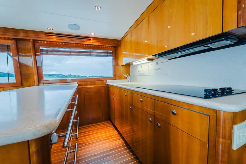 Water's Edge Yacht Photos Pics Luxurious kitchen interior of 2005 Hatteras Convertible 60 yacht with wooden cabinetry and modern appliances.