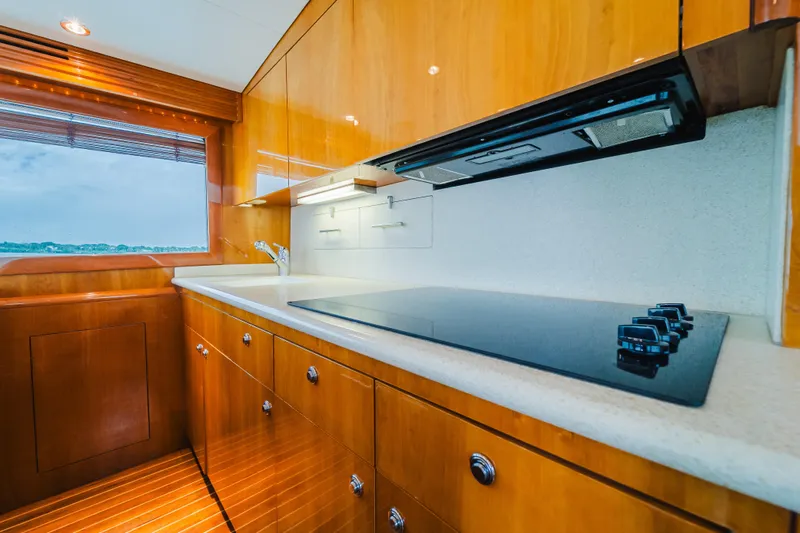 Water's Edge Yacht Photos Pics Luxurious kitchen interior of 2005 Hatteras Convertible 60 yacht with sleek wooden cabinetry.