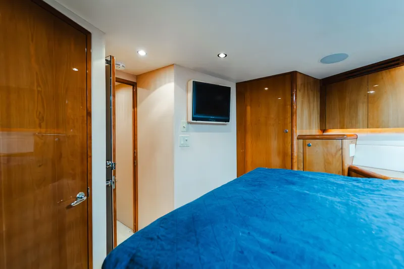 Water's Edge Yacht Photos Pics Luxurious cabin interior of 2005 Hatteras Convertible 60 yacht with wood paneling and blue bedding.