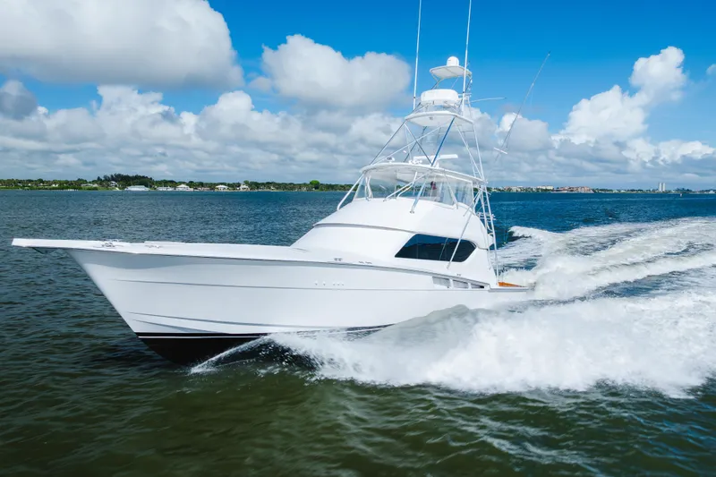 Water's Edge Yacht Photos Pics 2005 Hatteras Convertible 60 yacht cruising on open water under a clear blue sky.