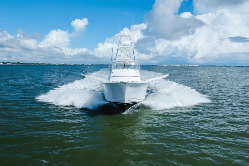 Water's Edge Yacht Photos Pics 2005 Hatteras Convertible 60 yacht cruising on open water under a blue sky.