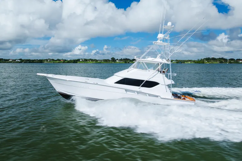 Water's Edge Yacht Photos Pics 2005 Hatteras Convertible 60 yacht cruising on open water under a cloudy sky.