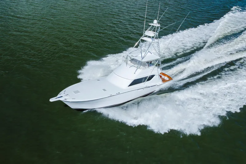 Water's Edge Yacht Photos Pics 2005 Hatteras Convertible 60 yacht cruising on open water, creating a dynamic wake.