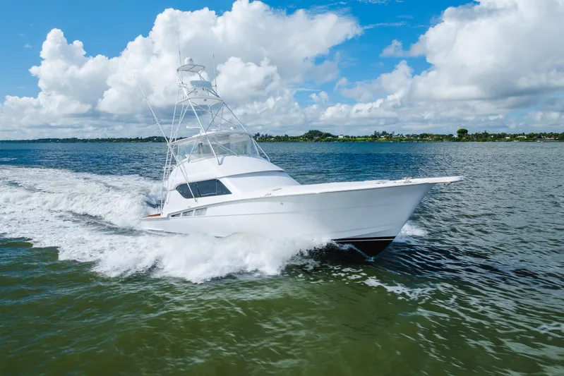 Water's Edge Yacht Photos Pics 2005 Hatteras Convertible 60 yacht cruising on open water under a blue sky.