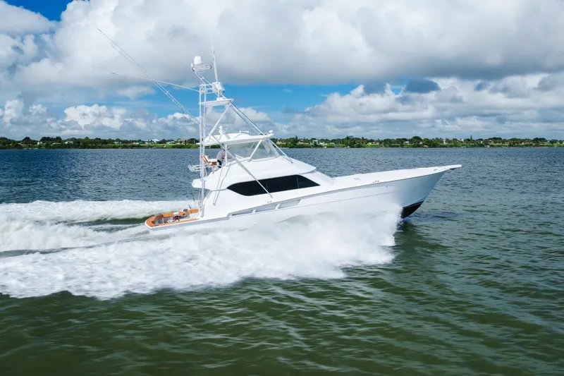 Water's Edge Yacht Photos Pics 2005 Hatteras Convertible 60 yacht cruising on open water under a cloudy sky.