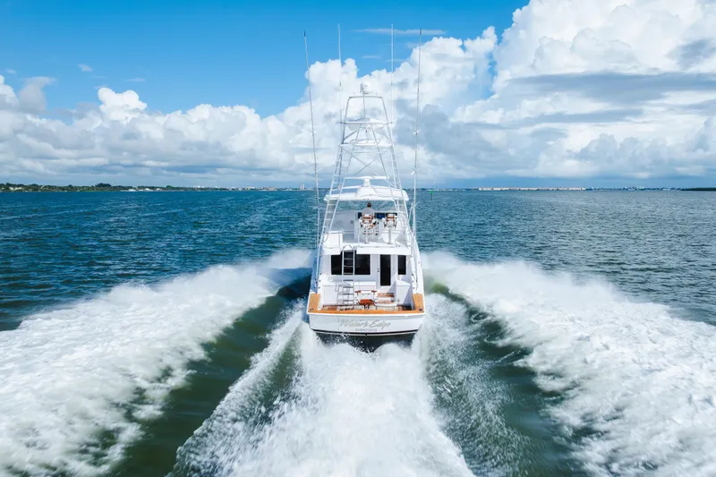 Water's Edge Yacht Photos Pics 2005 Hatteras Convertible 60 yacht cruising on open water under a blue sky.