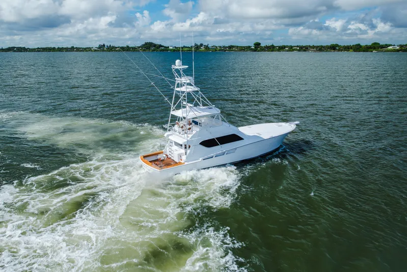 Water's Edge Yacht Photos Pics 2005 Hatteras Convertible 60 yacht cruising on open water under cloudy skies.