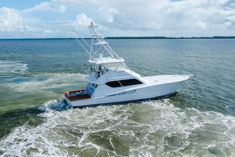 Water's Edge Yacht Photos Pics 2005 Hatteras Convertible 60 yacht cruising on open water under a cloudy sky.
