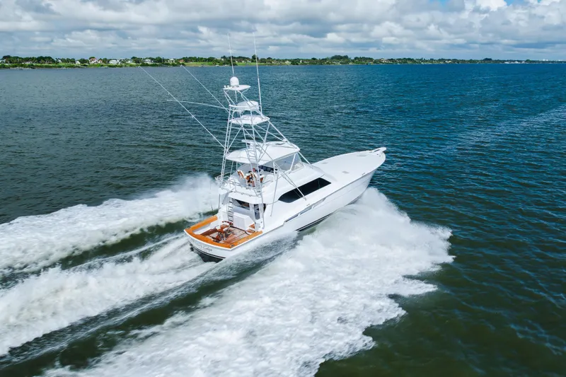 Water's Edge Yacht Photos Pics 2005 Hatteras Convertible 60 yacht cruising on open water under cloudy skies.