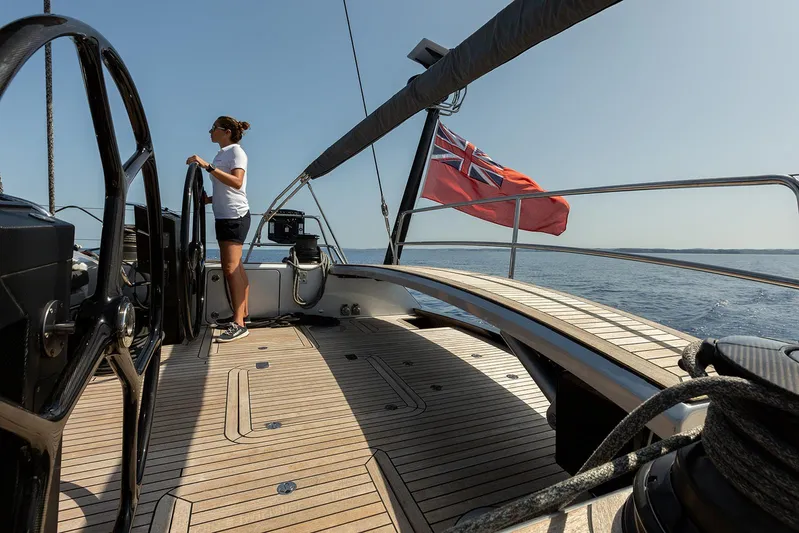Caiarossa Yacht Photos Pics Sailor steering Shipman 72 yacht, 2009 model, with red flag, on open sea.