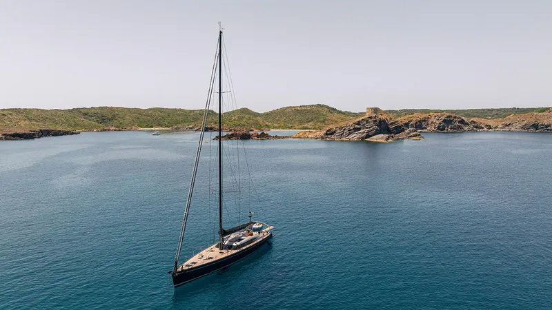 Caiarossa Yacht Photos Pics Sailing yacht Shipman 72 (2009) on serene blue waters near rocky coastline.