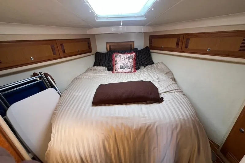 Assalt Weapon Yacht Photos Pics 2007 Cabo 35 Flybridge cabin with cozy bed, wooden storage, and overhead skylight.
