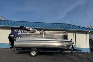 2024 Sun Tracker Party Barge 16 DLX pontoon boat on trailer, parked outdoors.