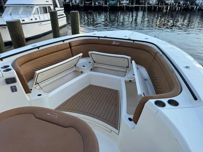 Yacht Photos Pics 2021 Scout 330 LXF boat interior with open storage compartments, docked by the water.