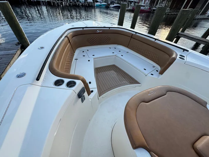  Yacht Photos Pics 2021 Scout 330 LXF boat interior with tan seating and wood accents at a dock.