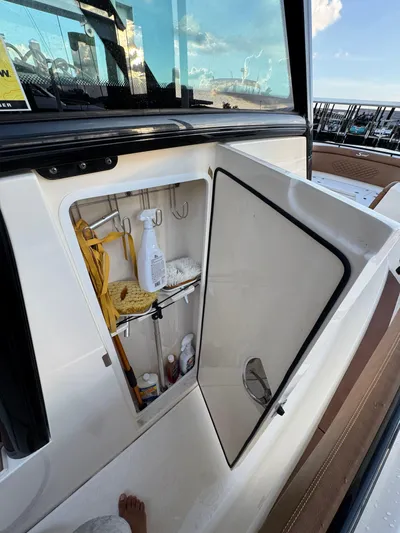  Yacht Photos Pics Open storage compartment on a 2021 Scout 330 LXF boat, containing cleaning supplies.