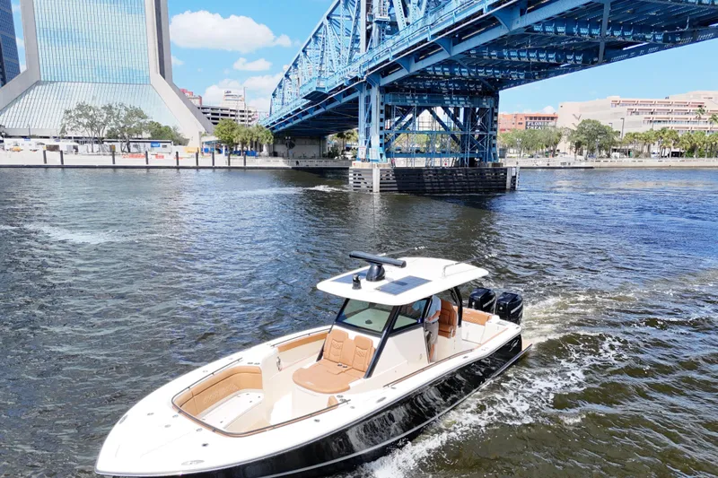  Yacht Photos Pics 2021 Scout 330 LXF boat cruising under a blue bridge in a cityscape setting.