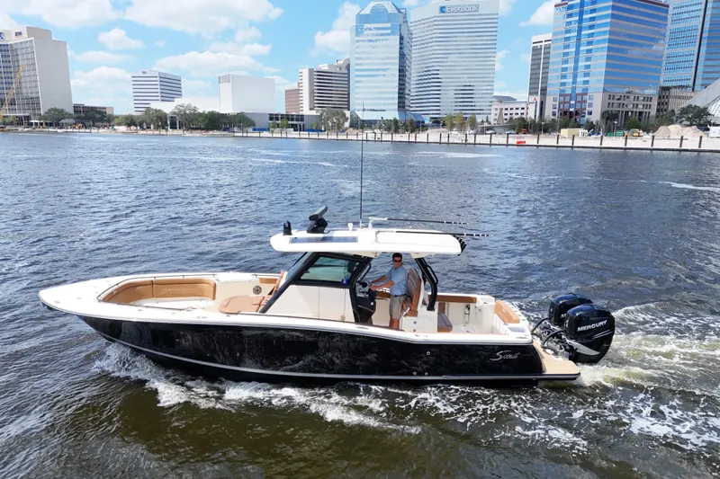  Yacht Photos Pics 2021 Scout 330 LXF boat cruising on a river with city skyline backdrop.
