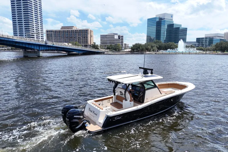  Yacht Photos Pics 2021 Scout 330 LXF boat cruising on urban river with cityscape background.