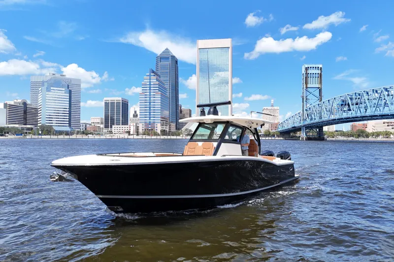  Yacht Photos Pics 2021 Scout 330 LXF boat cruising near city skyline and blue bridge on a sunny day.