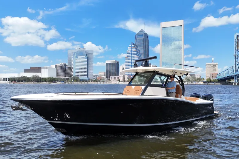  Yacht Photos Pics 2021 Scout 330 LXF boat cruising on a river with city skyline backdrop.