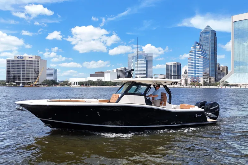  Yacht Photos Pics 2021 Scout 330 LXF boat cruising on a river with city skyline backdrop.