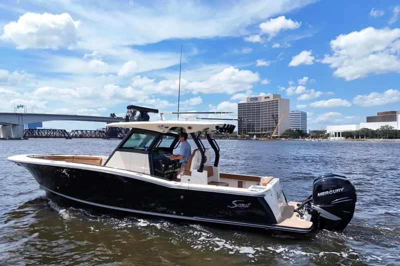  Yacht Photos Pics 2021 Scout 330 LXF boat cruising on a river with cityscape background.