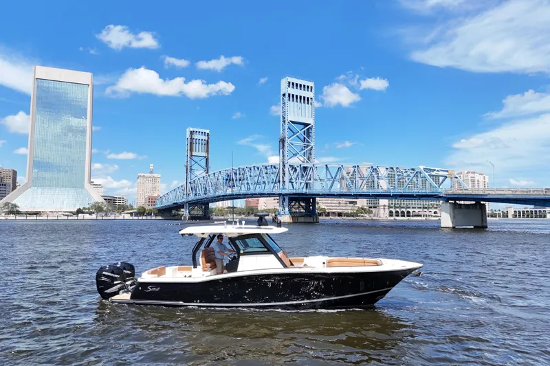  Yacht Photos Pics 2021 Scout 330 LXF boat cruising near a blue bridge and city skyline.