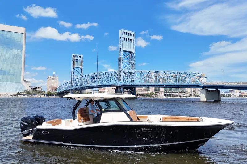  Yacht Photos Pics 2021 Scout 330 LXF boat cruising near a blue bridge under a clear sky.