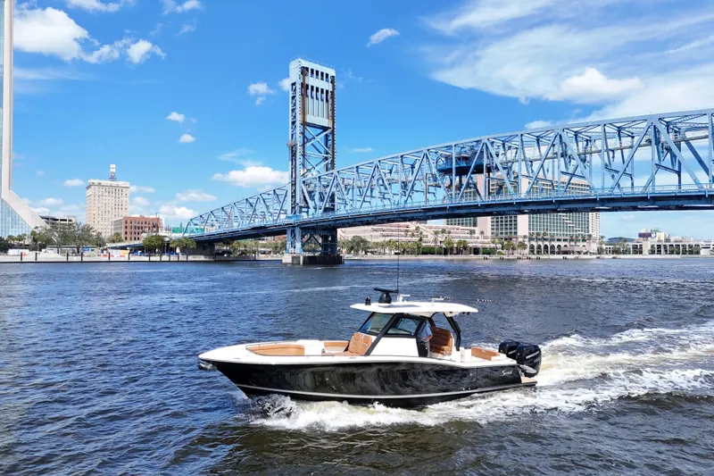  Yacht Photos Pics 2021 Scout 330 LXF boat cruising under a blue bridge on a sunny day.