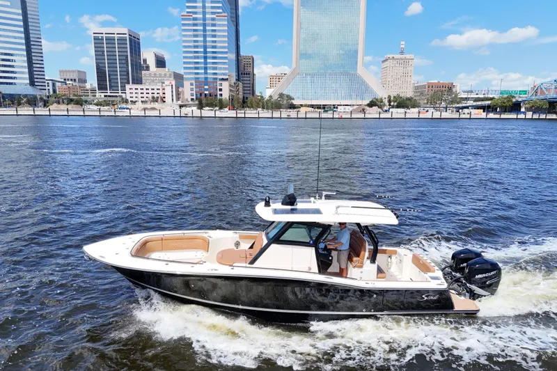  Yacht Photos Pics 2021 Scout 330 LXF boat cruising on a river with city skyline backdrop.