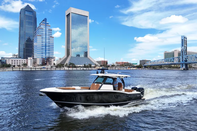  Yacht Photos Pics 2021 Scout 330 LXF boat cruising on a river with city skyline backdrop.