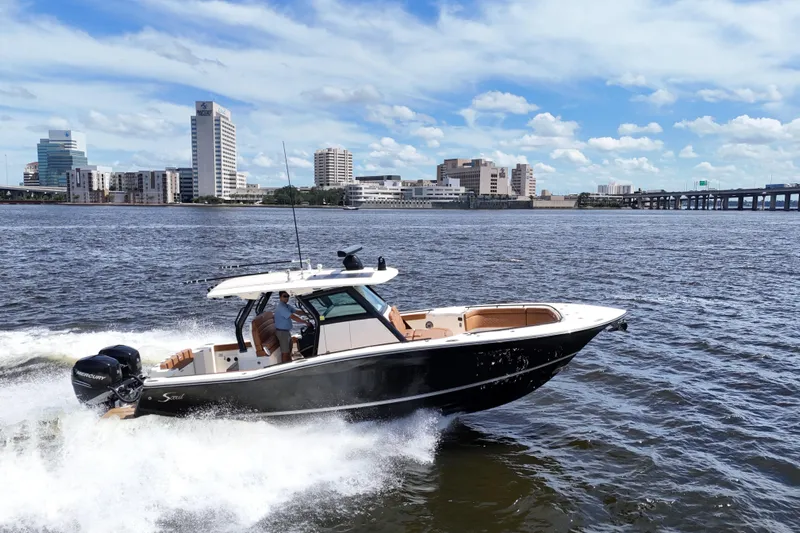  Yacht Photos Pics 2021 Scout 330 LXF boat cruising on a river with city skyline backdrop.