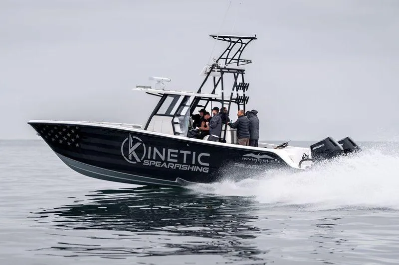Reaper Yacht Photos Pics 2024 Invincible 33 Catamaran speeding on water, featuring "Kinetic Spearfishing" branding.