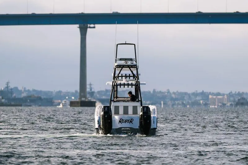 Reaper Yacht Photos Pics 2024 Invincible 33 Catamaran cruising under a bridge on a calm waterway.