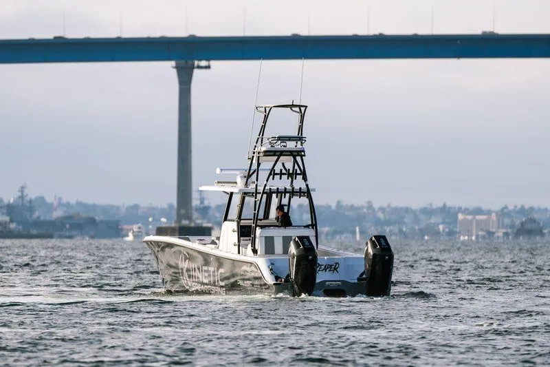 Reaper Yacht Photos Pics 2024 Invincible 33 Catamaran on water near bridge, showcasing sleek design and powerful engines.