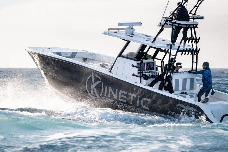 Reaper Yacht Photos Pics 2024 Invincible 33 Catamaran navigating ocean waves, featuring Kinetic Spearfishing branding.