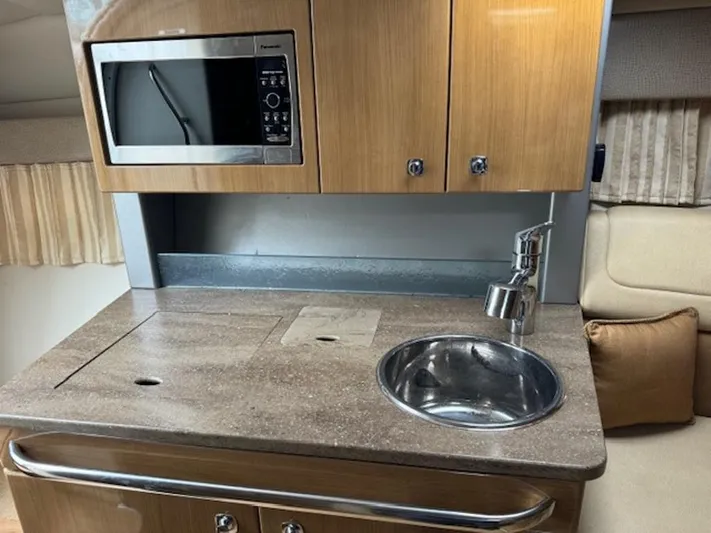  Yacht Photos Pics 2013 Formula 350 Sun Sport kitchenette with microwave, sink, and wooden cabinetry.