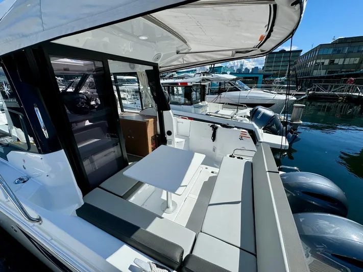 Pearl Yacht Photos Pics 2024 Jeanneau NC 895 boat with outdoor seating and table, docked at a marina.