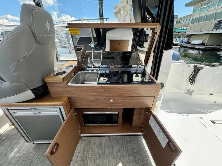 Pearl Yacht Photos Pics 2024 Jeanneau NC 895 boat interior with kitchenette, featuring stove, sink, and microwave.