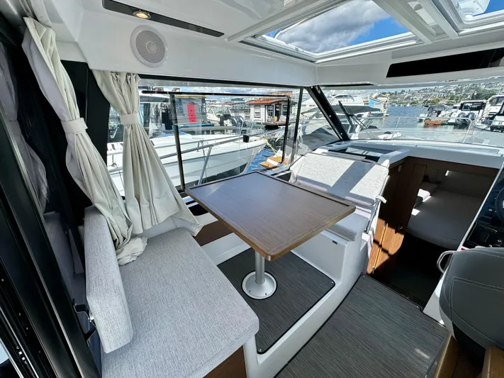 Pearl Yacht Photos Pics Interior of 2024 Jeanneau NC 895 boat with seating, table, and waterfront view.